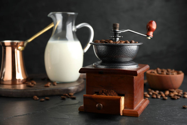 Vintage manual coffee grinder with beans and powder on black table - Fotó, kép