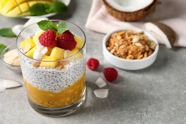 Delicious chia pudding with mango, raspberries and granola on light grey table - Фото, зображення