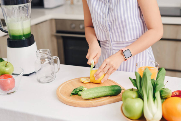 Frau schneidet Gemüse für Smoothie in der heimischen Küche. Gesundes Konzept. - Foto, Bild