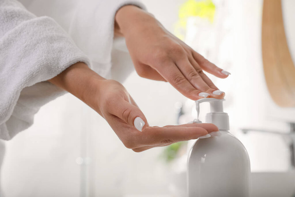Teenage girl using gel in bathroom, closeup. Skin care cosmetic - Zdjęcie, obraz
