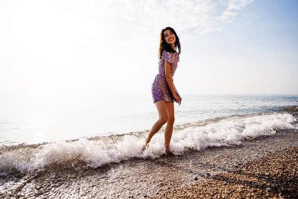 Portrait of young woman walking on the beach on sunrise - Foto, immagini