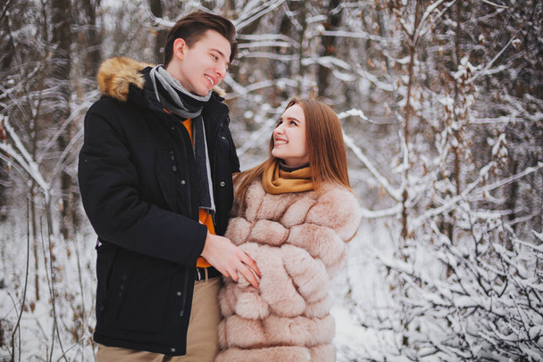Genç ve güzel bir çiftin soğuk bir kış günü dışarıda birlikte vakit geçirdiği adamın, soğuk bir günde kızı sıcak tutmak için kıza sarıldığı fotoğraf. Romantik bir buluşma. - Fotoğraf, Görsel