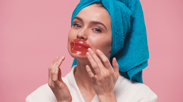 pretty woman in terry bathrobe on head applying lip mask isolated on pink - Photo, Image
