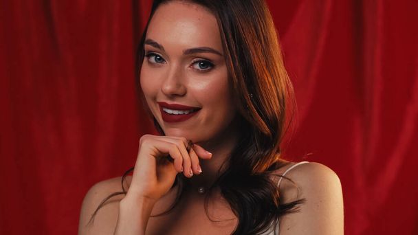 flirty young woman smiling at camera on red - Фото, зображення