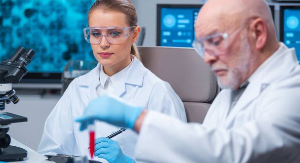 Professor and doctor work in a modern scientific laboratory using equipment and computertechnologies. Group of scientists make research and develop new vaccines. Science and healthcare concept. - Фото, зображення