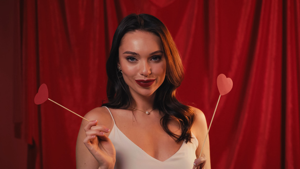 pretty woman holding hearts on sticks and smiling on red - Foto, Bild