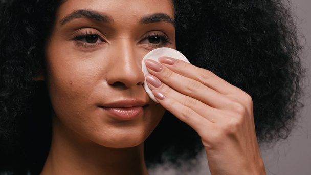 close up of african american woman wiping face with cotton pad isolated on grey - Photo, Image