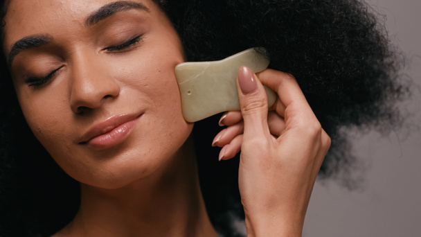 african american woman using gua sha stone isolated on grey - Photo, Image