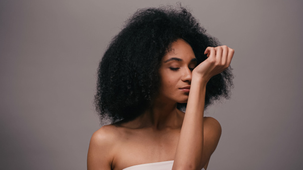 молода афроамериканка насолоджується запахом парфумів ізольована на сірому
 - Фото, зображення