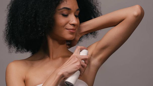 mujer afroamericana feliz aplicando desodorante aislado en gris - Foto, imagen