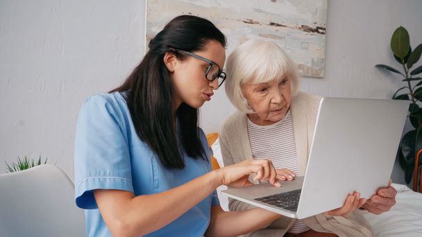 brunette nurse showing aged woman how to use laptop - Photo, Image