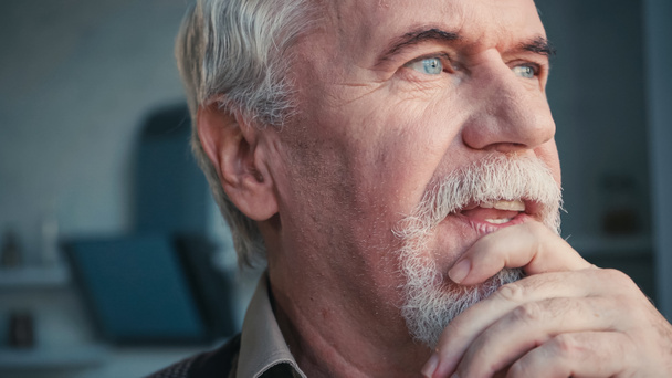 close up of pensive and retired man looking away while touching face - Foto, immagini