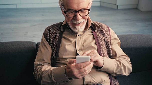 幸せな定年退職した男性がスマートフォンでメールを送ると  - 写真・画像