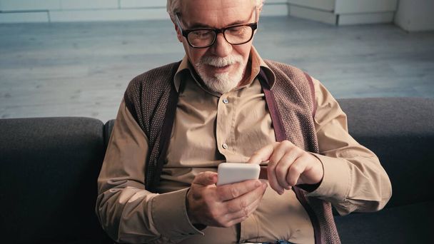Gözlüklü neşeli emekli adam akıllı telefondan mesaj atıyor.  - Fotoğraf, Görsel