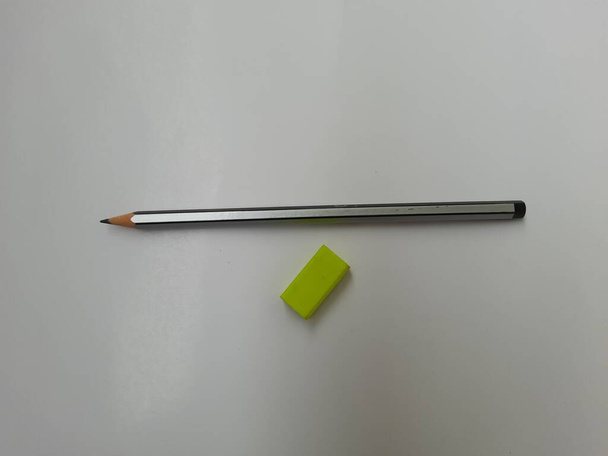 Primer plano de lápiz de color negro o gris y artículos de papelería de educación de caucho verde aislados sobre fondo blanco - Foto, imagen