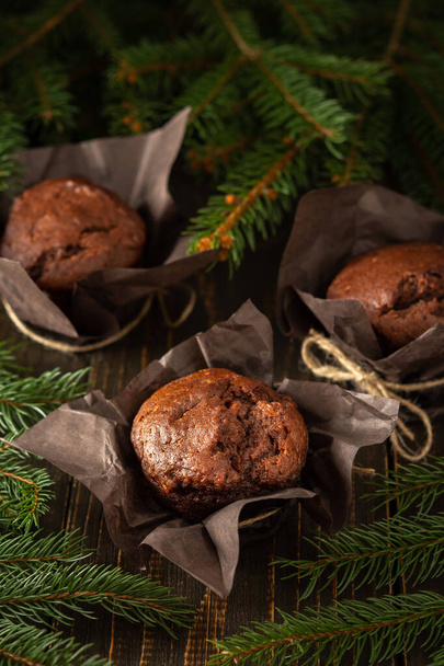 Delicious chocolate muffins on dark wooden background among fir branches, Merry Christmas and Happy New Year - Foto, Imagem