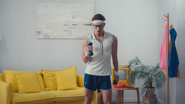 focused sportsman lifting weight in living room, retro sport concept - Foto, immagini