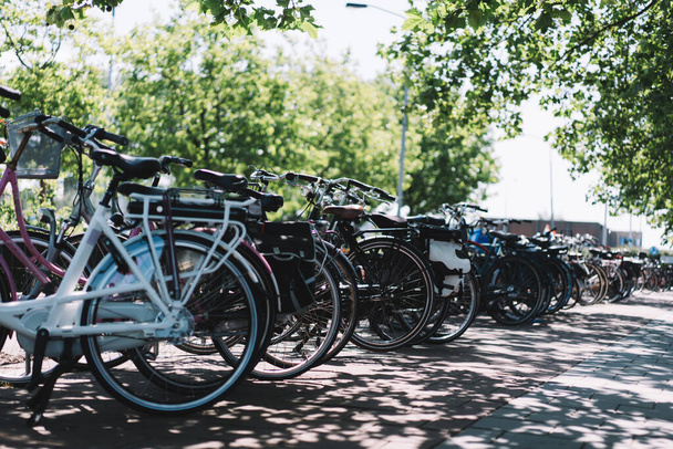 Bike transportation for free public using in metropolitan city, crowded parking with safety lockers for ecological vehicles, concept of healthy lifestyle and tourism on handlebar bicycles - Fotografie, Obrázek