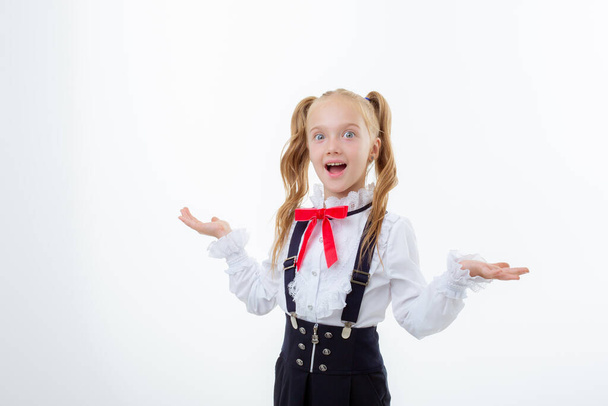 a little schoolgirl girl in a school uniform is isolated on a white background - Photo, Image