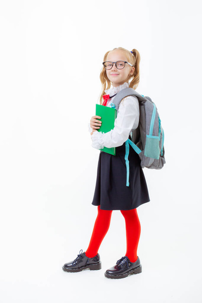 маленькая школьница в школьной форме держит книгу на белом фоне - Фото, изображение