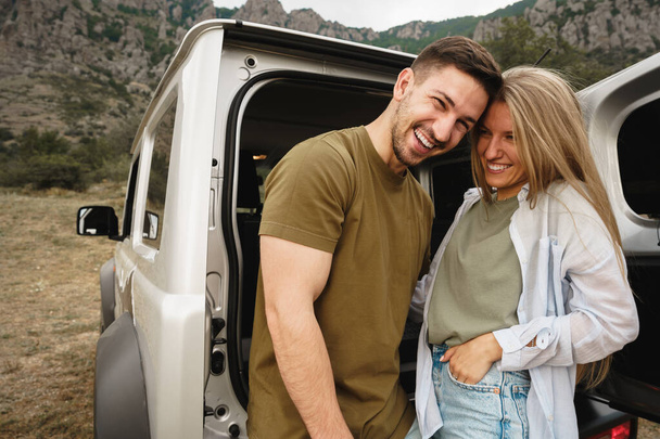 Young happy couple on a road trip sitting in car trunk - Foto, afbeelding