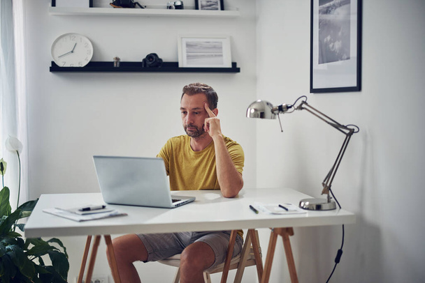 Adult caucasian man working on a laptop at home. - Φωτογραφία, εικόνα