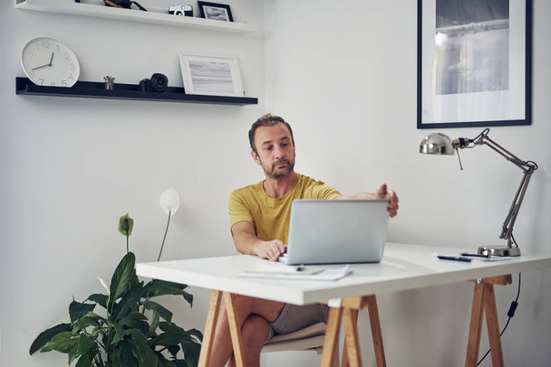 Felnőtt fehér férfi dolgozik egy laptop otthon. - Fotó, kép