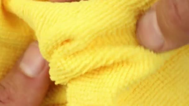 prueba de manos y estira el paño amarillo del polvo de la microfibra, vista de cerca en la textura del tejido sintético que absorbe el agua - Metraje, vídeo