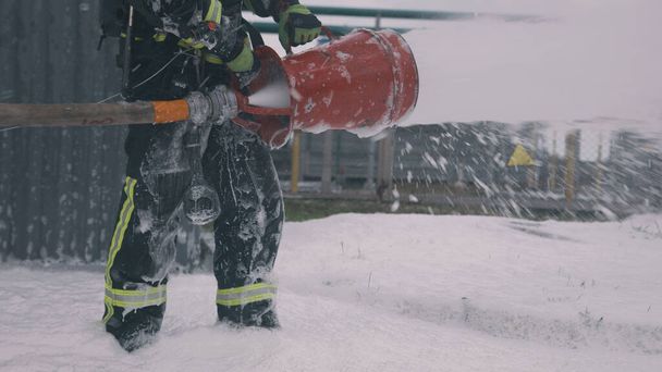 Unrecognizable fireman standing in foam - Foto, imagen