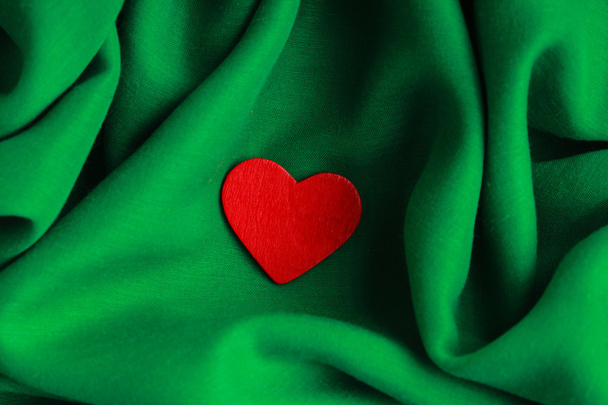 Red wooden decorative heart on green folds background. - Fotografie, Obrázek
