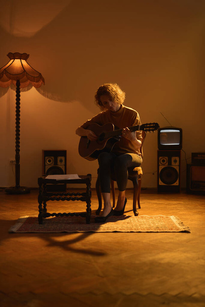 Nő játszik akusztikus gitáron egy retro vintage szobában. - Fotó, kép