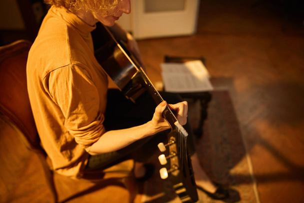 Frau spielt Akustikgitarre im Retro-Vintage-Raum. - Foto, Bild