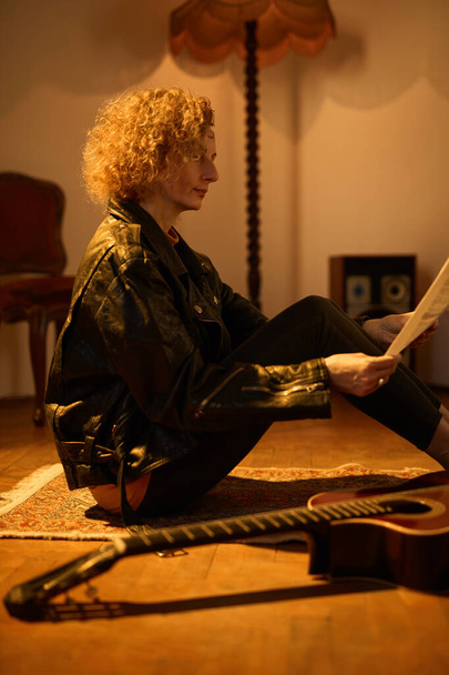Kobieta gra na gitarze akustycznej w pokoju retro vintage. - Zdjęcie, obraz