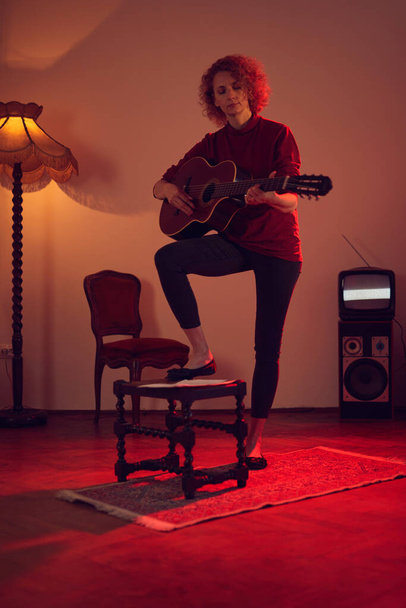 Eski moda bir odada akustik gitar çalan bir kadın.. - Fotoğraf, Görsel