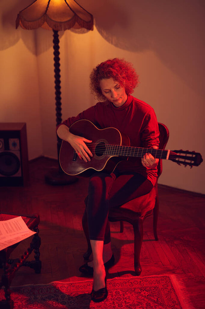 Nő játszik akusztikus gitáron egy retro vintage szobában. - Fotó, kép