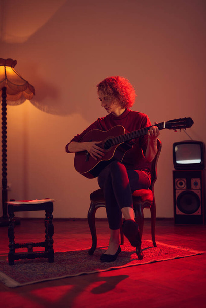 Mulher tocando guitarra acústica em um quarto vintage retro. - Foto, Imagem