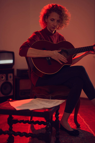 Woman playing acoustic guitar in a retro vintage room. - Photo, Image