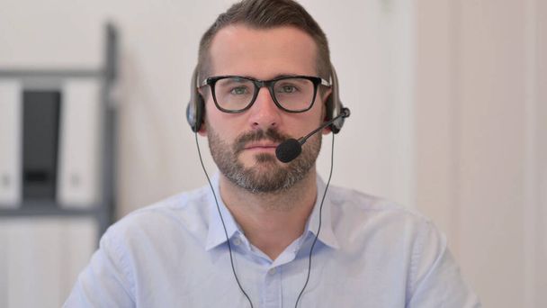 Retrato del hombre de mediana edad con auriculares mirando a la cámara  - Foto, Imagen