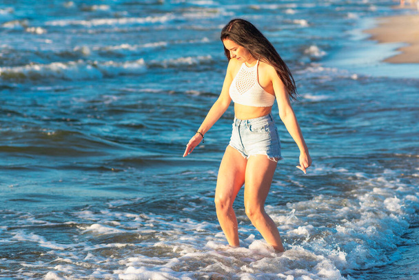 Young woman playing in the sea in summer. woman enjoying in sea water.Cheerful young woman having fun on the beach. She is relaxed in the sea water and enjoys on vacation. - Foto, imagen