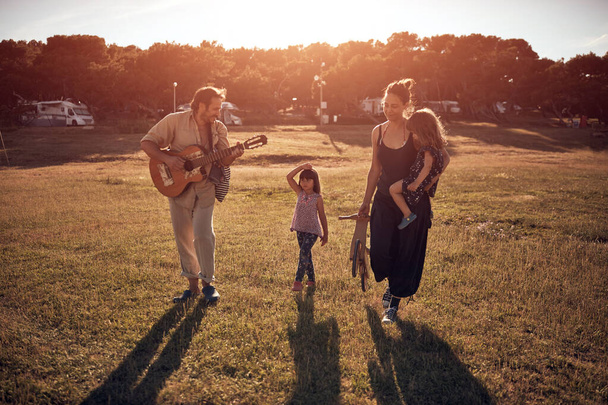 Tatilde bir aile, şarkı söylemek, gitarda müzik çalmak ve yaz havasının tadını çıkarmak.. - Fotoğraf, Görsel