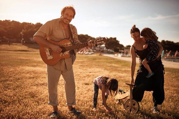 Familia en vacaciones, cantando, tocando música en una guitarra y disfrutando de vibraciones veraniegas. - Foto, imagen