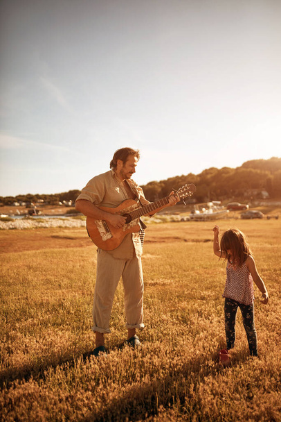 Isä ja tytär soittavat musiikkia, laulavat lauluja ja nauttivat kesätunnelmista.. - Valokuva, kuva