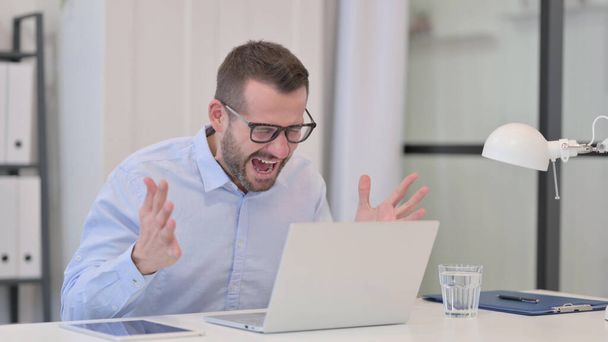 Középkorú férfi kiabál, miközben dolgozik a Laptop  - Fotó, kép