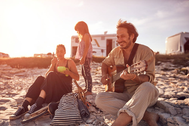 Семья в отпуске, поет, играет на гитаре и наслаждается летними вибрациями. - Фото, изображение