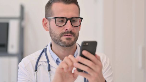Портрет лікаря середнього віку за допомогою смартфона
  - Фото, зображення