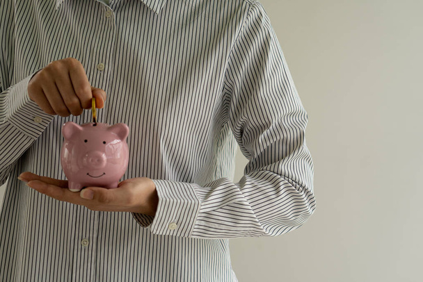 mano de niña sosteniendo una moneda en una alcancía, concepto de ahorro de dinero - Foto, imagen