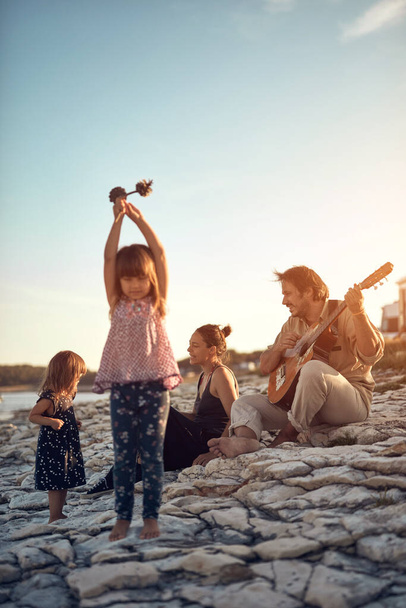 Perhe lomalla, laulamassa, soittamassa musiikkia kitaralla ja nauttimassa kesätunnelmista. - Valokuva, kuva
