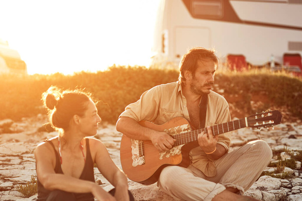 Muž zpívá své přítelkyni na pláži. - Fotografie, Obrázek