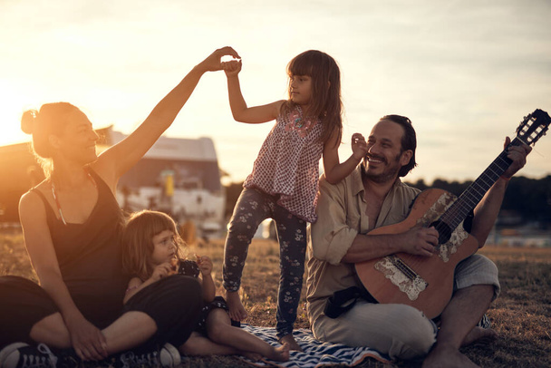 Familie op vakantie, zingen, muziek spelen op een gitaar en genieten van de zomerse vibes. - Foto, afbeelding