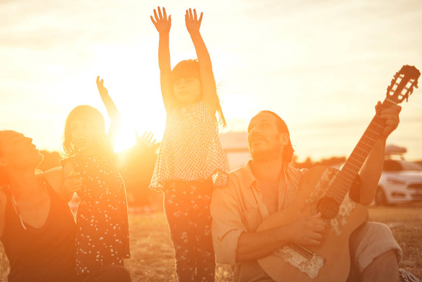Família em férias, cantando, tocando música em uma guitarra e desfrutando de vibrações de verão. - Foto, Imagem